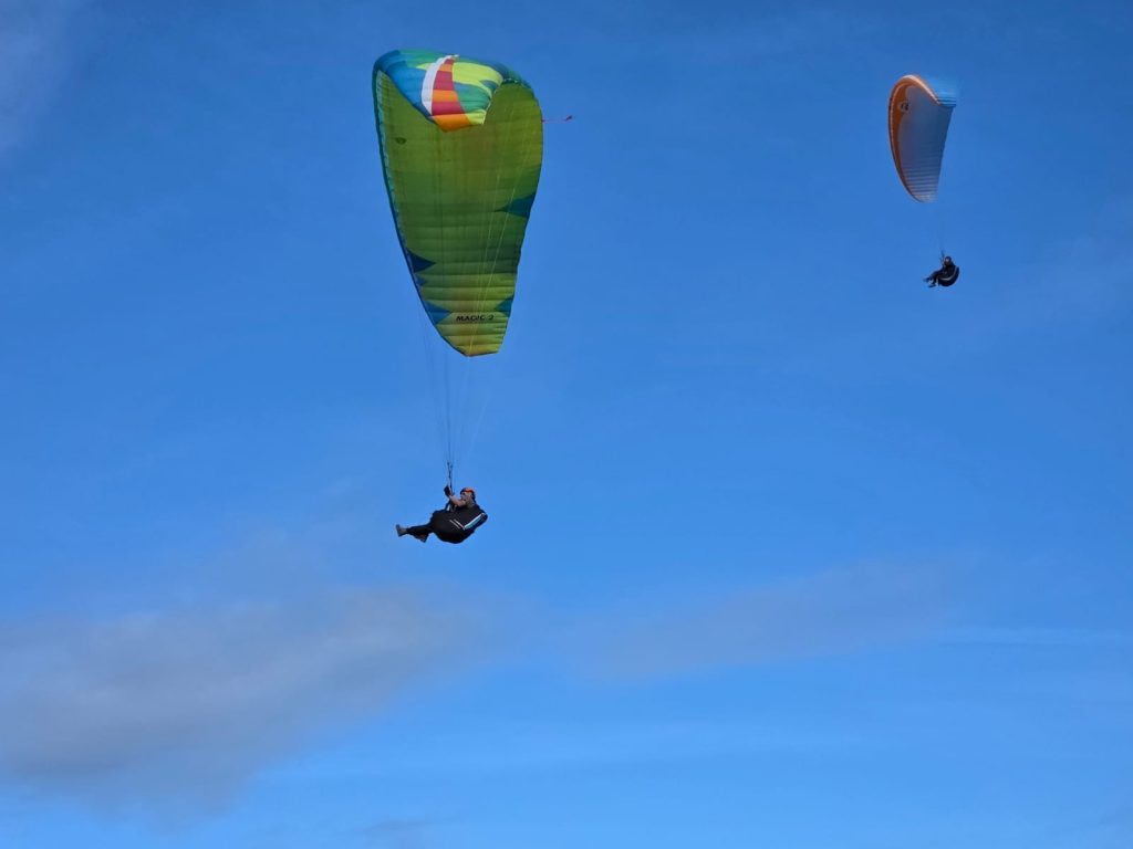 Michael under the green/blue wing orange helmet (on the left) flying in Morocco with Mid-Wales ParaGliding Centre